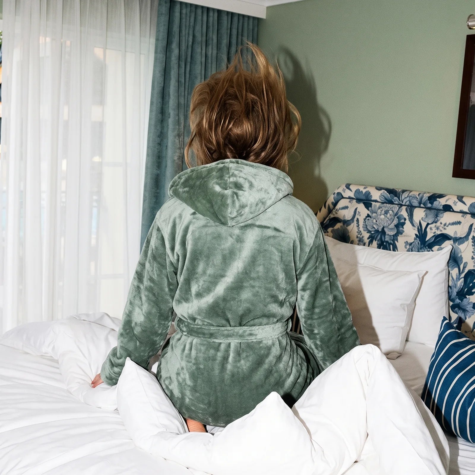 Kvinna i morgonrock landar i hotellsäng bäddad med A Funky Dream från Boe Leisure