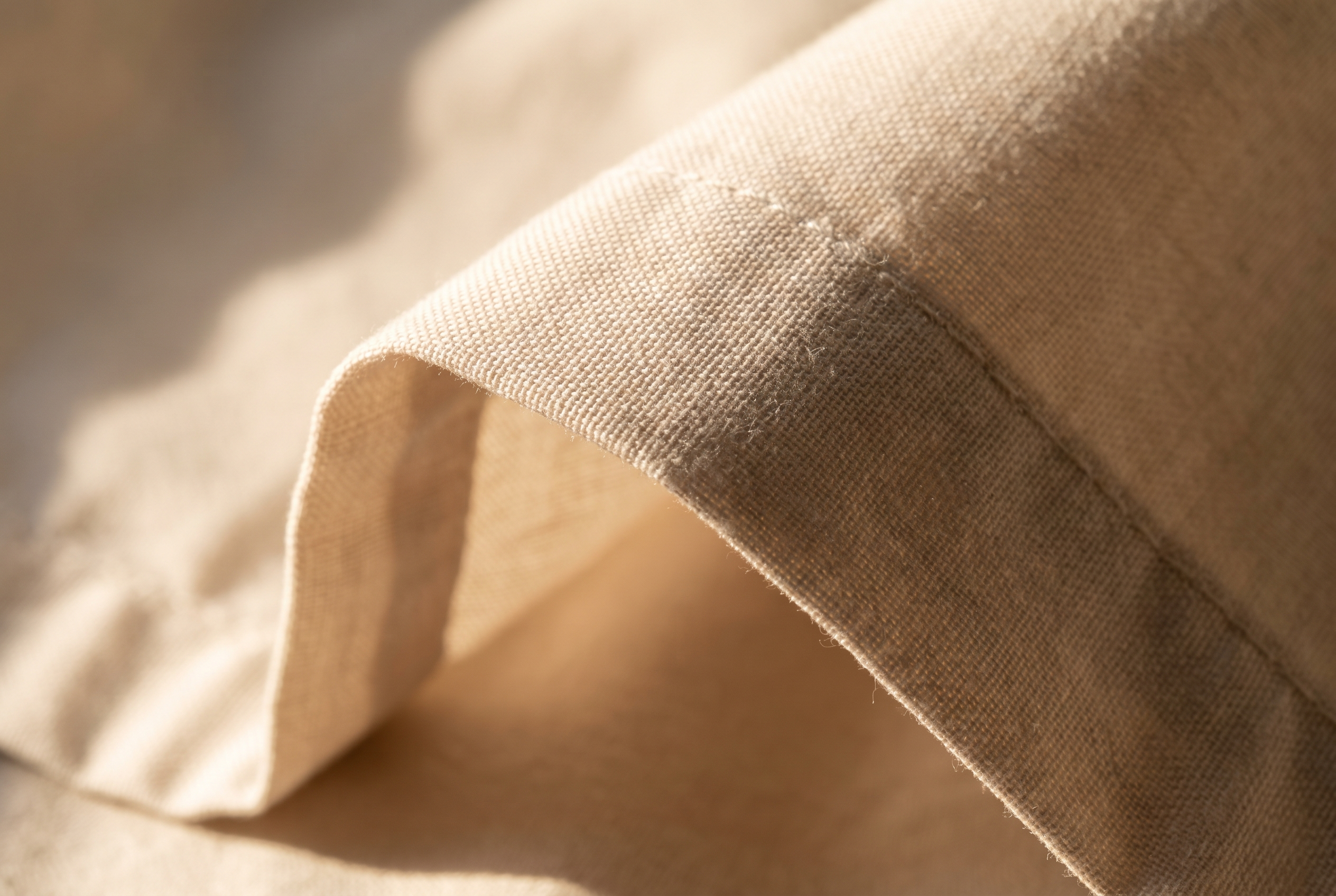 Närbild på vävytan i ett krispt percale-sänglinne där trådstrukturen framträder i sidoljus