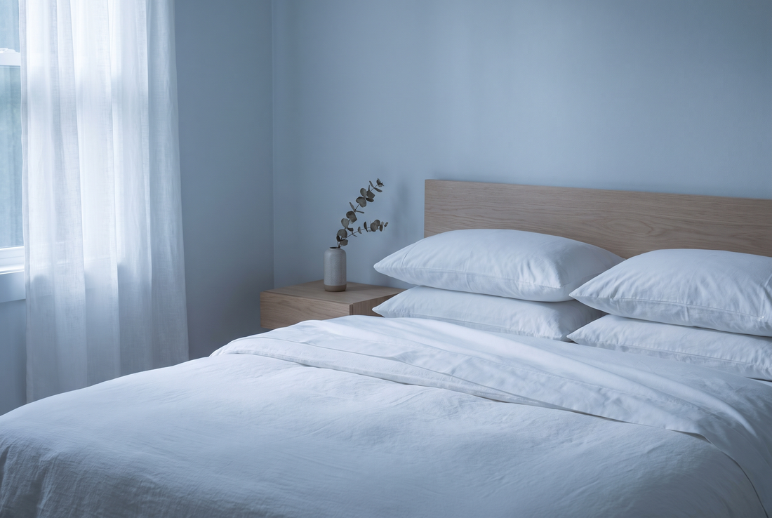 Rent, ljust sänglinne mjukt bäddat i stilla morgonljus – en bild av hudnära, kemiskt trygg textil
